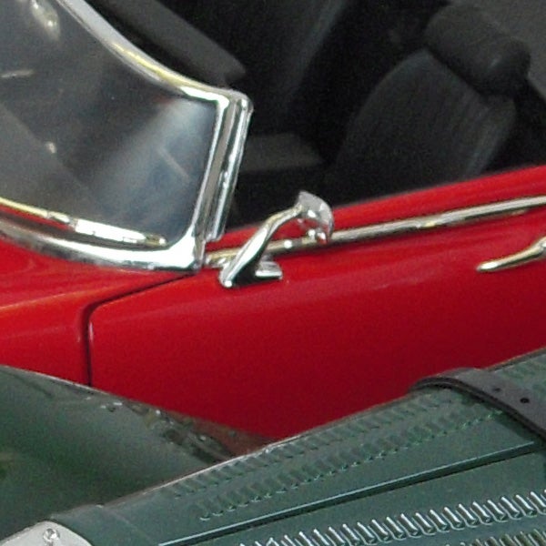 Close-up photo of a vehicle's shiny red exterior and chrome details.Close-up of a classic red car with chrome details.