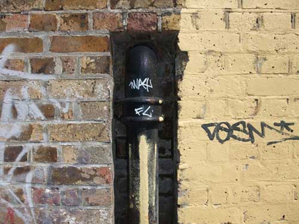 Graffiti on urban wall captured with Fujifilm Finepix F100fd.Graffiti on urban brick wall and pipe.