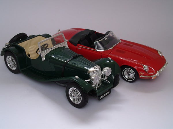 Photo of two model cars, a green classic and a red sports car.Detail of two model classic cars in green and red