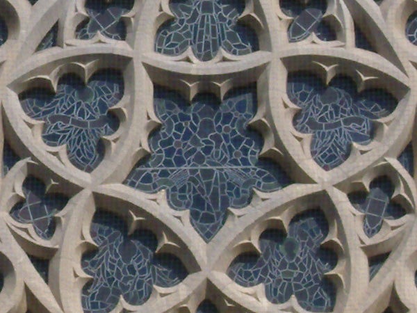 Photograph of ornate stone carvings and blue glass detailsStone pattern architectural detail with blue mosaic.