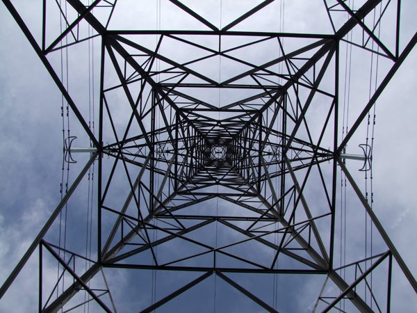 Upward view of a metal electricity pylon against a cloudy sky.Upward view through metal electricity pylon structure against cloudy sky.