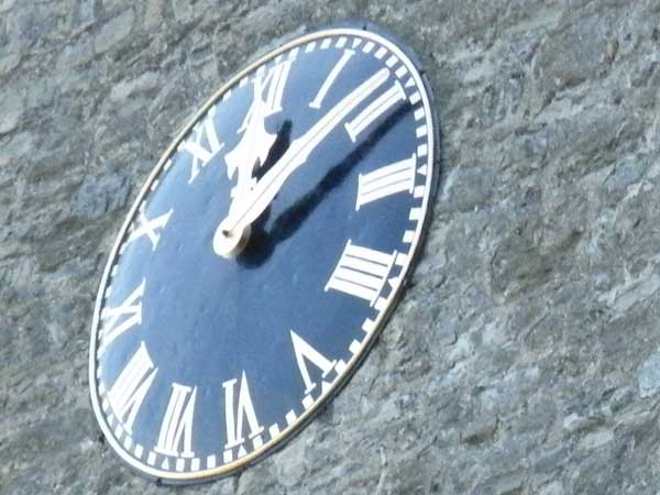 Close-up of an oval clock face against a stone background.Close-up of clock face taken with Fujifilm Finepix S8100fd.