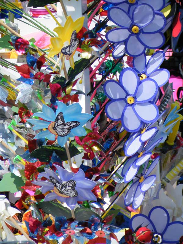 Colorful artificial flowers with butterfly decorations in sunlight.Colorful artificial flowers and butterflies in bright sunlight.