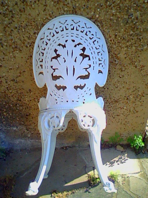 White cast iron garden chair with intricate backrest design