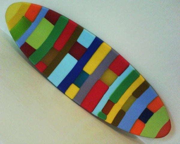 Colorful abstract surfboard-shaped art piece on a white background.Colorful abstract pattern on a curved surface.