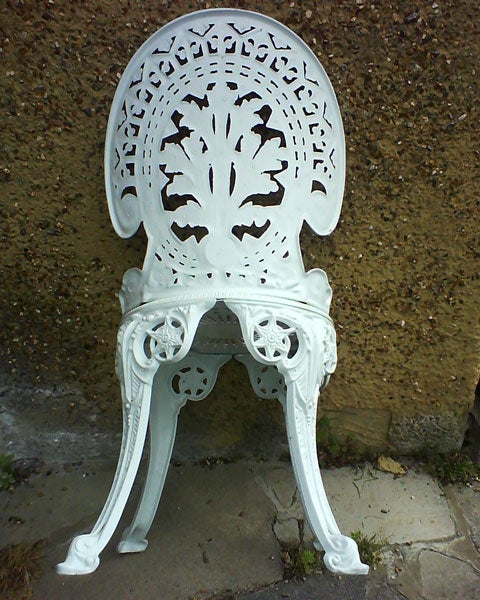 Ornate white metal chair against a textured wall.Intricately designed white metal chair against a wall.