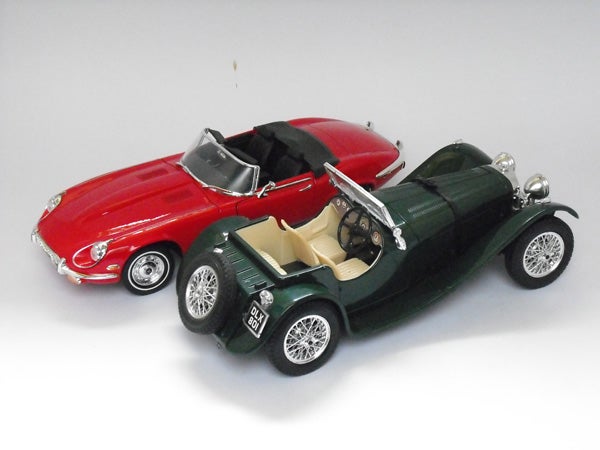 Two vintage model cars on a white background.Two vintage toy cars, one red and one green.