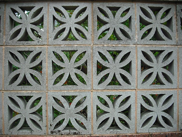 Decorative concrete block wall pattern with foliage background.Decorative concrete block wall with leaf patterns.