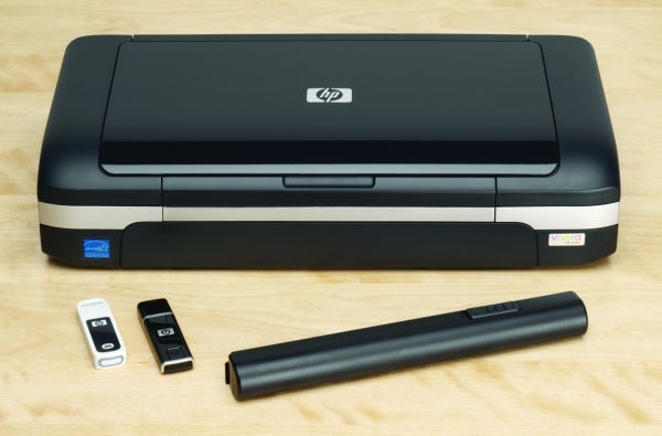 HP OfficeJet H470 printer with accessories on wooden surface.