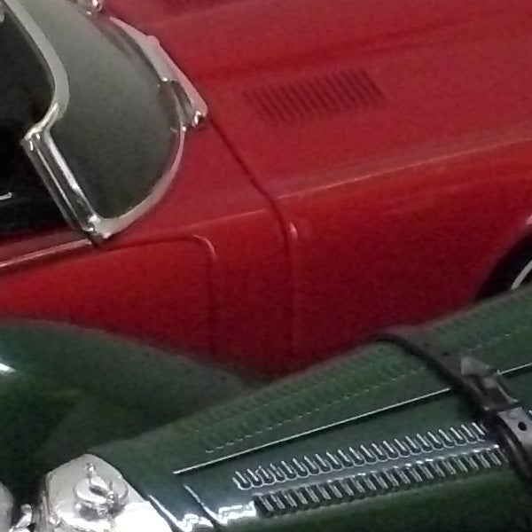 Close-up of a red and green vintage car's bodywork.Close-up of a vintage red and green car.