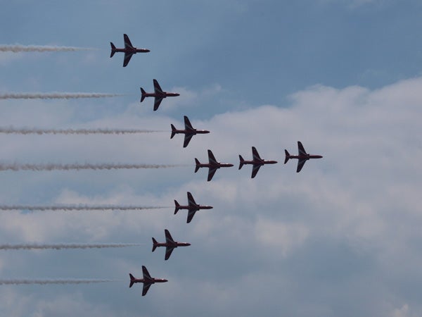 Photograph of an aerial display by jets captured with Olympus E-520.Nine jets flying in formation with smoke trails against sky.