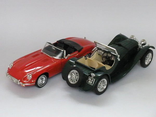 Two die-cast model cars photographed on a gray surfaceTwo toy cars on a plain background