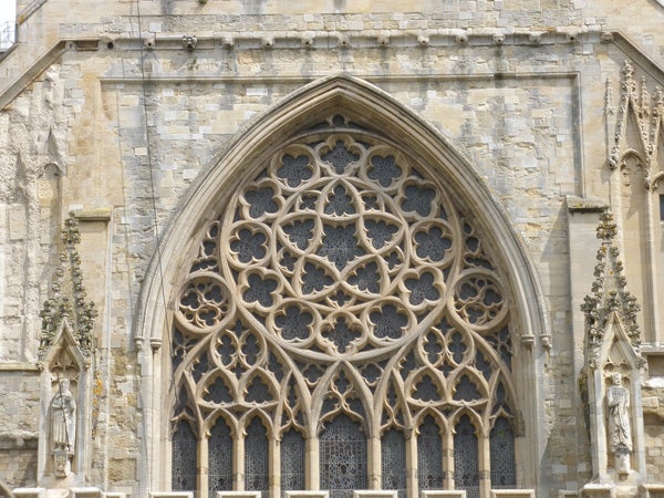 Intricate gothic window architecture on stone church facade.Detailed stonework of gothic church window facade.