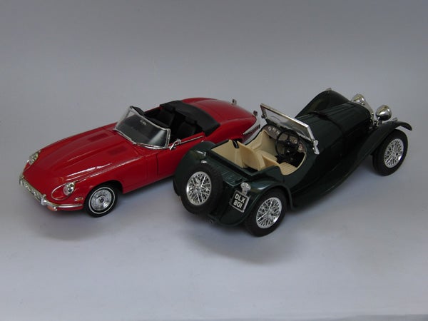 Two model cars on a gray backgroundTwo model cars, a red and a green classic convertible.