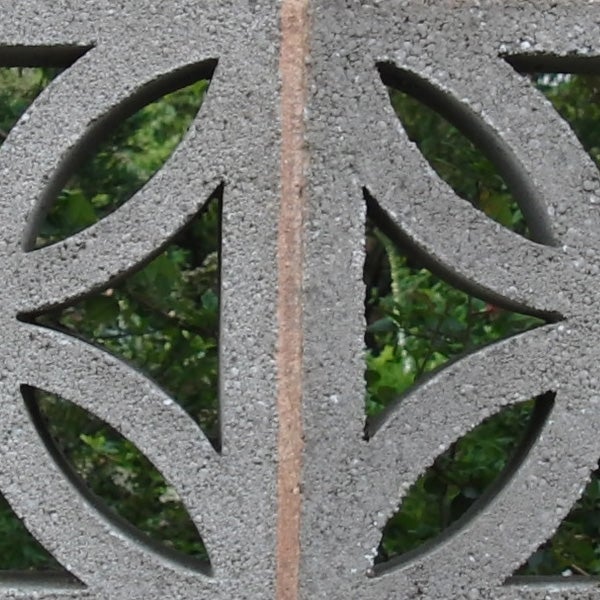 Concrete wall with decorative cut-out patterns.