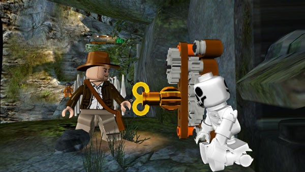Screenshot of Lego Indiana Jones character with an enemy and a key.Lego Indiana Jones game screenshot with characters and artifact.