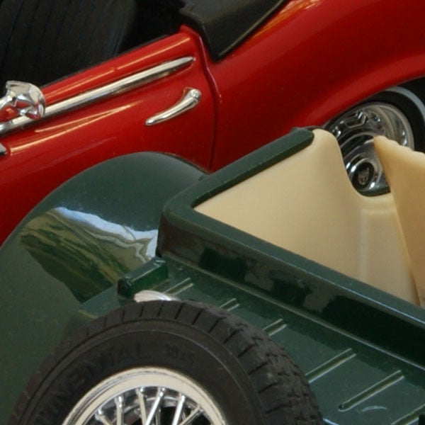 Close-up of a red car and green toy vehicle wheels.