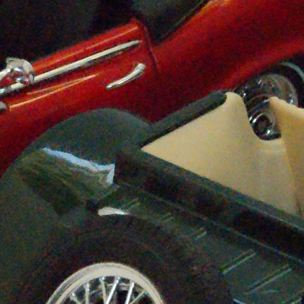 Close-up of a red vintage car toy model.Red vintage car reflected on a dark shiny surface.