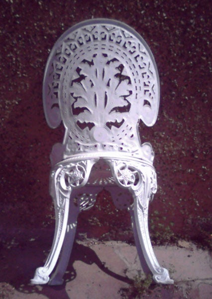 White ornate metal chair against a red background.