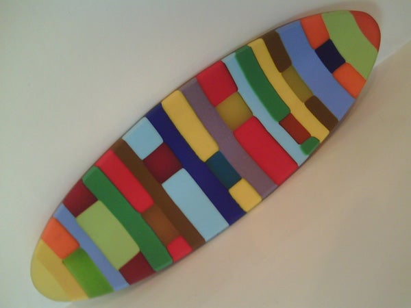 Colorful abstract surfboard-shaped art installation on white background.Colorful mosaic surfboard on white background.