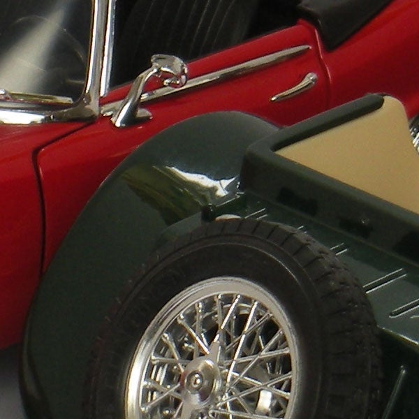 Close-up of a red vintage car model wheel and mirror.