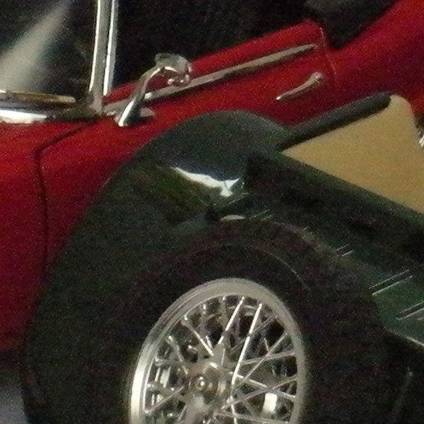 Photo sample from Nikon CoolPix S550 of a red car and wheel.Close-up of a red car's rear wheel and fender.