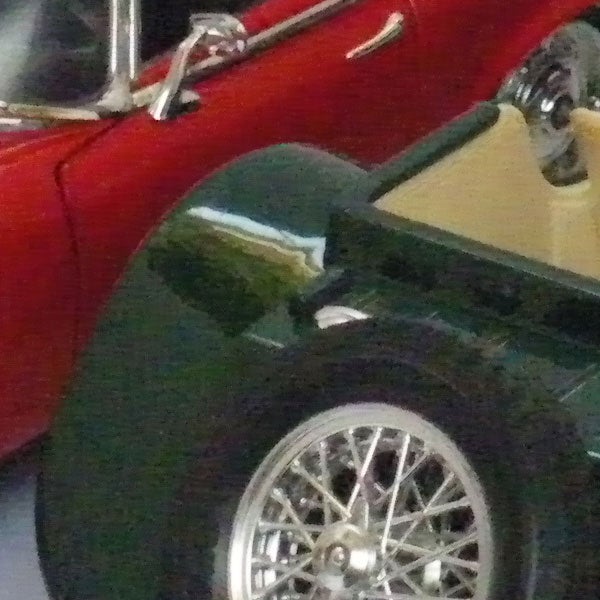 Close-up of a model car wheel and part of the bodyClose-up of a vintage red car model's details