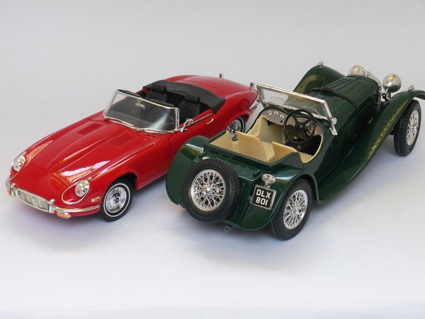 Red and green vintage model cars on white background.Model cars, red Jaguar E-Type and green vintage sports car.