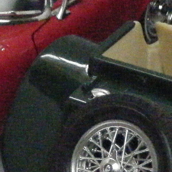 Low-resolution photo of a vintage car wheel.Close-up photo of a vintage car wheel and fender.