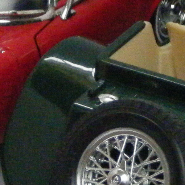 Close-up of vintage cars with focus on green car's front wheel.Close-up of a vintage car's front wheel and fender.