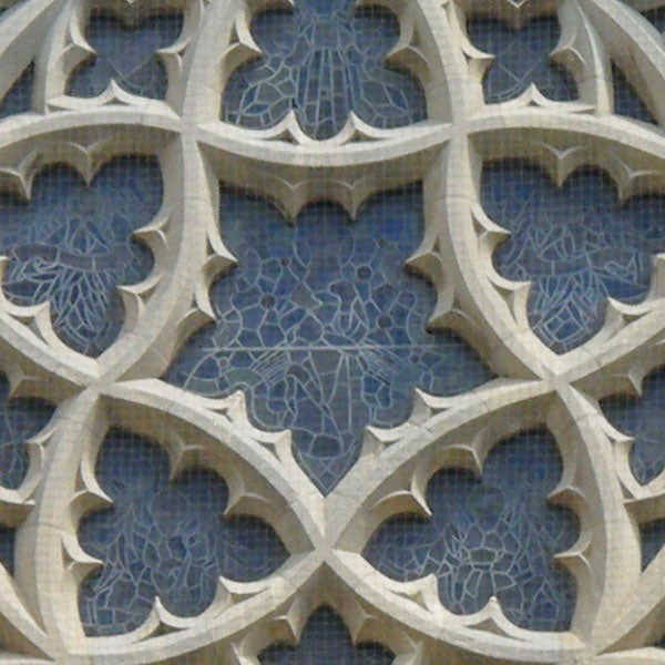 Ornate stone window tracery with blue background.Close-up of intricate stone lattice work against a blue background.