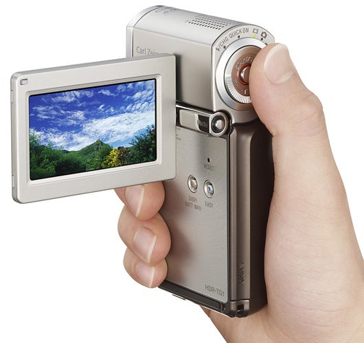 Hand holding Sony HDR-TG3 camcorder with flip-out screen.Hand holding Sony HDR-TG3 camcorder with open screen.