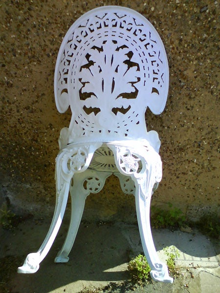 White ornate plastic chair against a concrete wall.White vintage chair with intricate design shadows