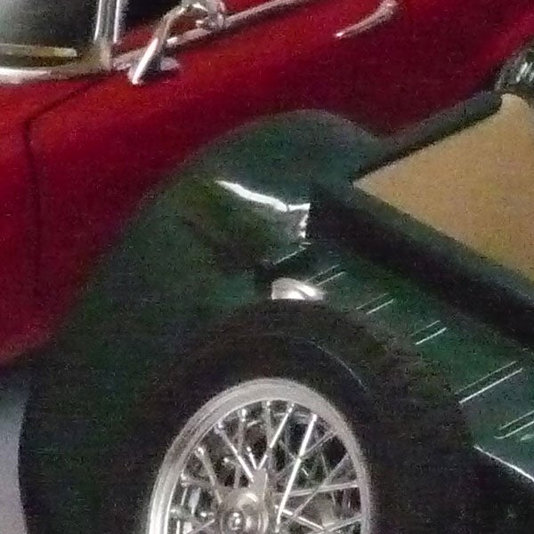 Close-up of car wheel and fender with a blur effect.Photo taken with Panasonic Lumix showing a red car's reflection.