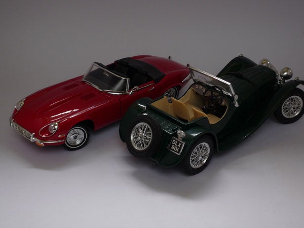 Two model cars, a red convertible and a green classic roadster.Two model cars, one red and one green, displayed together.