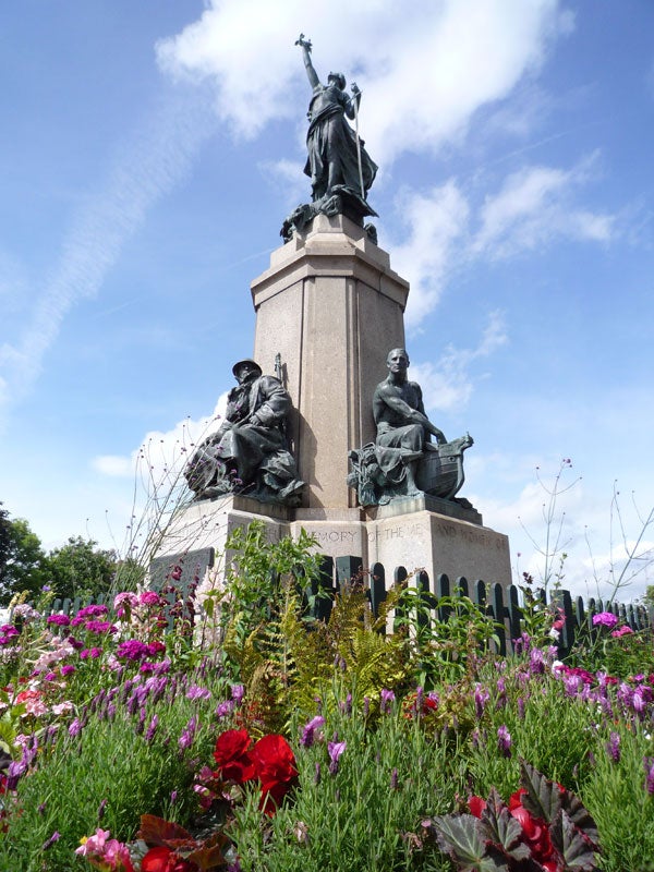 Monument surrounded by colorful flowers under blue skyPhotograph of a monument with vibrant flowers in foreground.