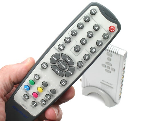 Hand holding AVerMedia TV tuner remote with product in background.AVerMedia AVerTV Hybrid remote control and TV tuner box.