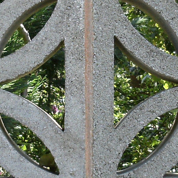 Close-up of intricate metalwork with foliage background.Close-up of intricate metal fence design with foliage background.