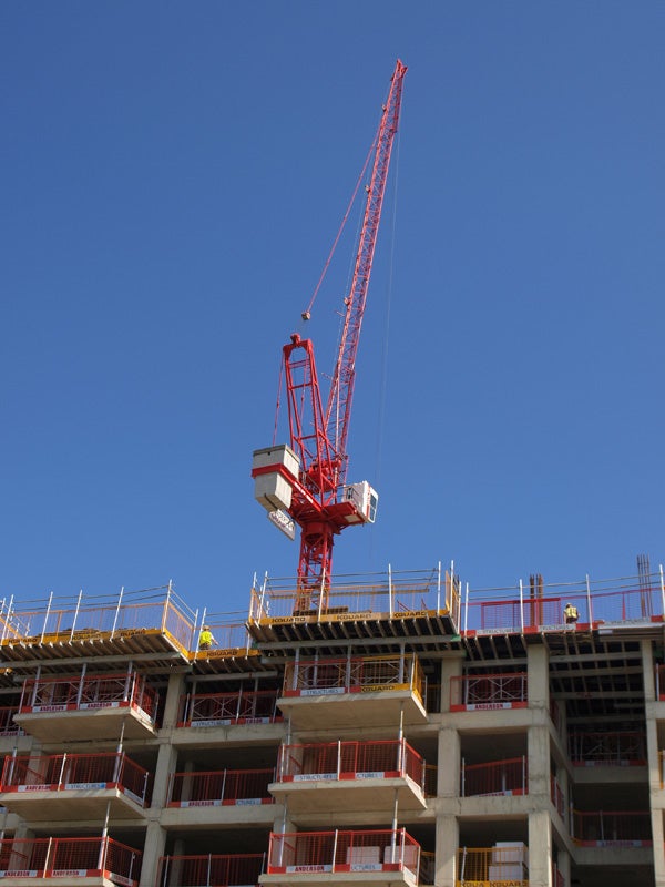 Red crane at construction site with clear blue skyClear sky behind red construction crane at building site