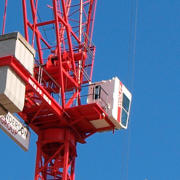 Close-up of a red crane against a blue sky.Close-up of Olympus E-420 camera on top of crane.