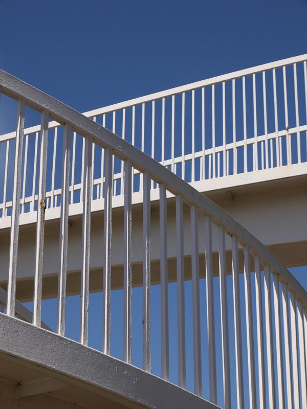 White balcony railing against a clear blue sky.White outdoor staircase railing against a blue sky.