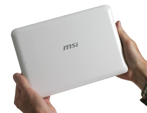 Person holding an MSI Wind notebook computer.Hand holding MSI Wind U100 netbook with logo