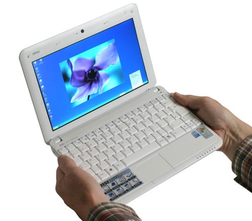 Person holding an open MSI Wind notebook with Windows XP.