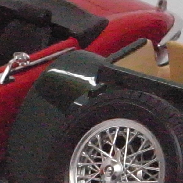 Close-up of car wheel with red bodywork.Close-up of a toy car wheel and fender.