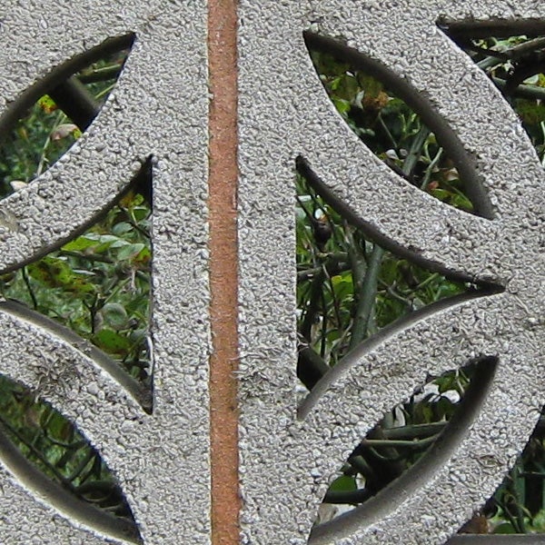 Close-up of intricate metal grate design with foliage background.Decorative metal garden bench with a frost coating.