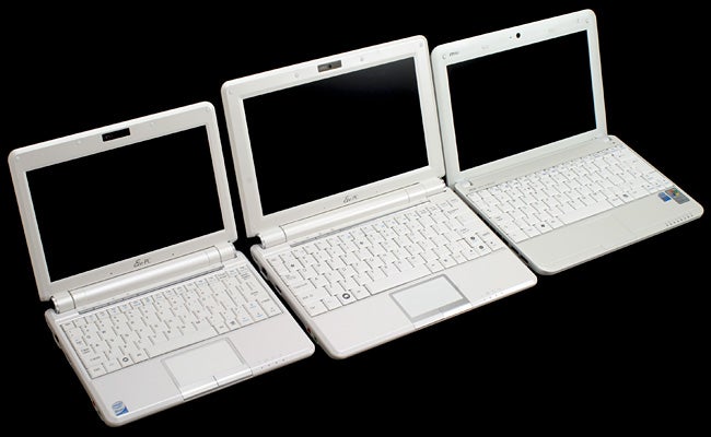 Three Asus Eee PC 1000 netbooks on a black background.Three Asus Eee PC 1000 laptops with open lids.