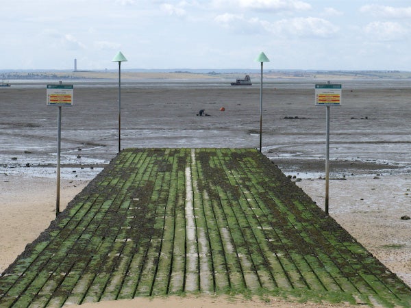 Moss-covered slipway leading to a beach at low tide.