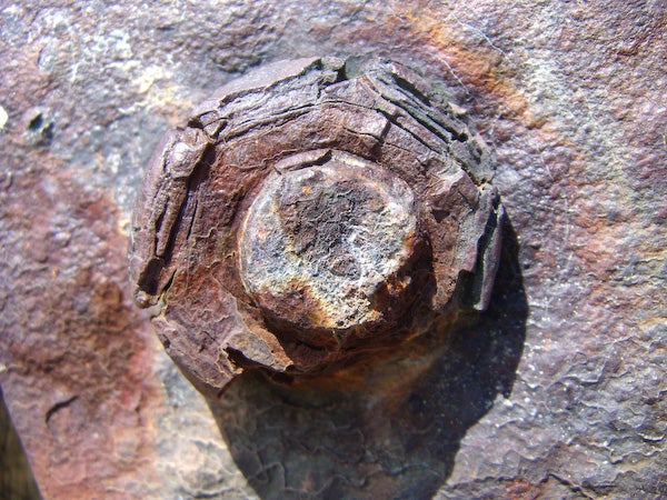 Rusted bolt head embedded in weathered rock surface.