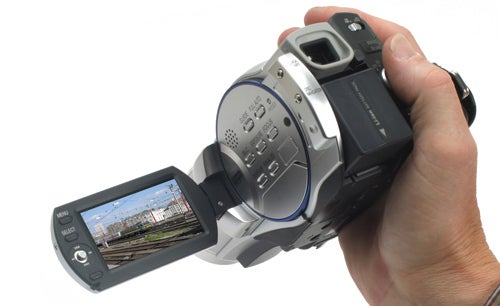 Hand holding Hitachi DZ-BD70E camcorder with display screen open.Hand holding Hitachi DZ-BD70E camcorder with LCD screen visible.