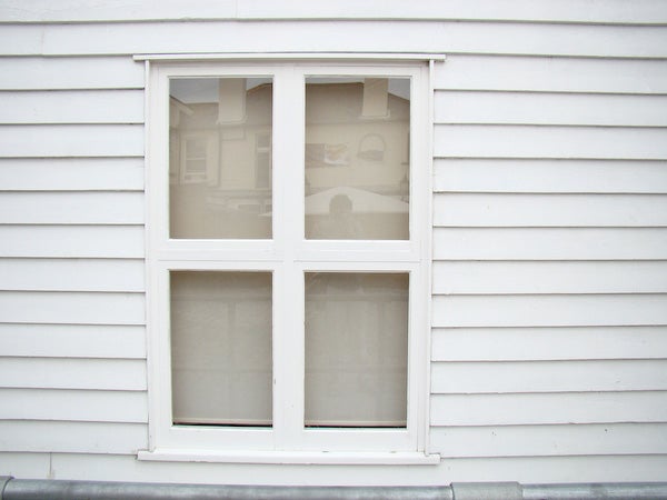 White window on a house with siding.White four-pane window on a house with siding.